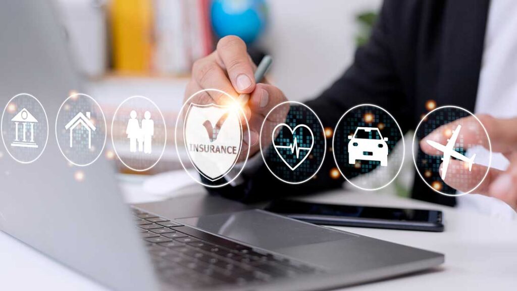 A family reviews insurance documents together at a dining table with papers and a laptop.